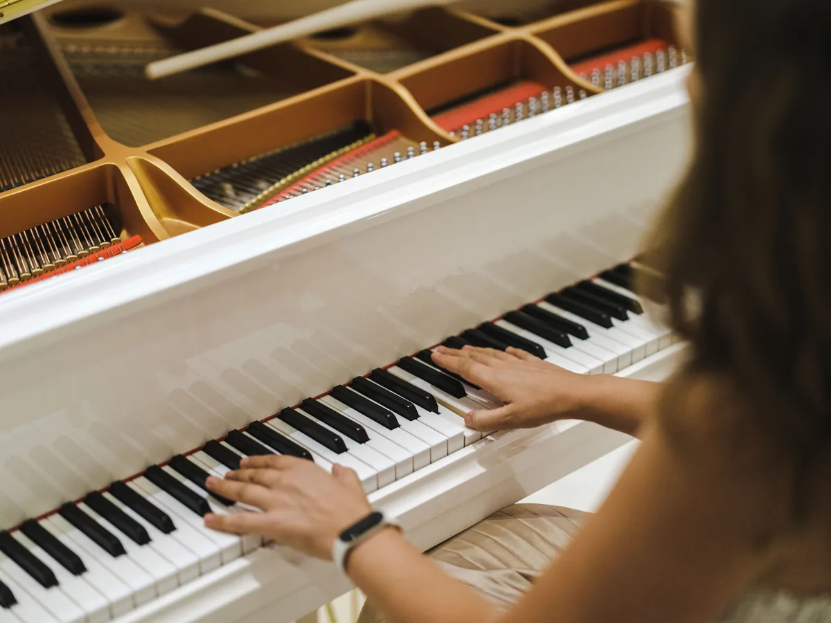 Manos tocando las teclas de un piano de cola, aprendiendo a tocar un instrumento musical